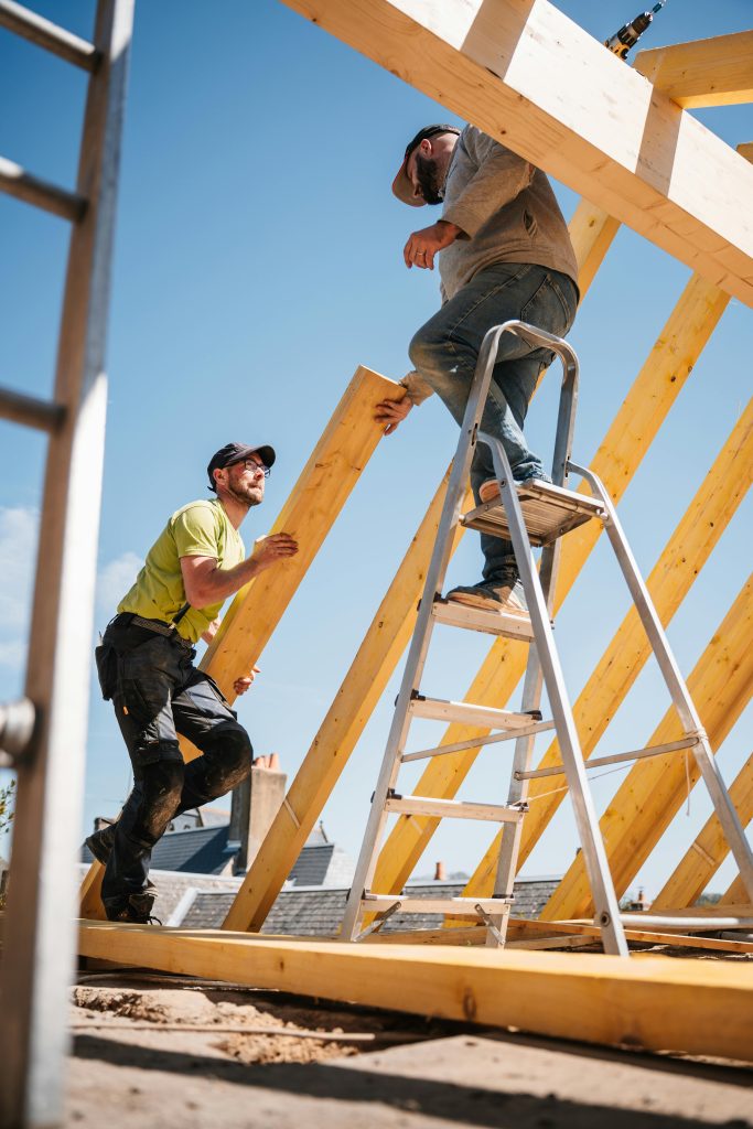 Couvreur professionnel inspectant une charpente avant rénovation de toiture dans le 93
